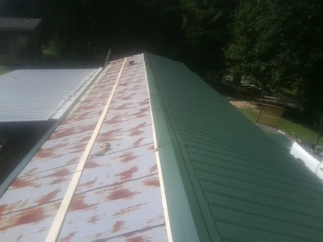Old rusted panels beside newly installed green metal roofing — Wind Damage Roof Repair by Roofing Brothers in Reading