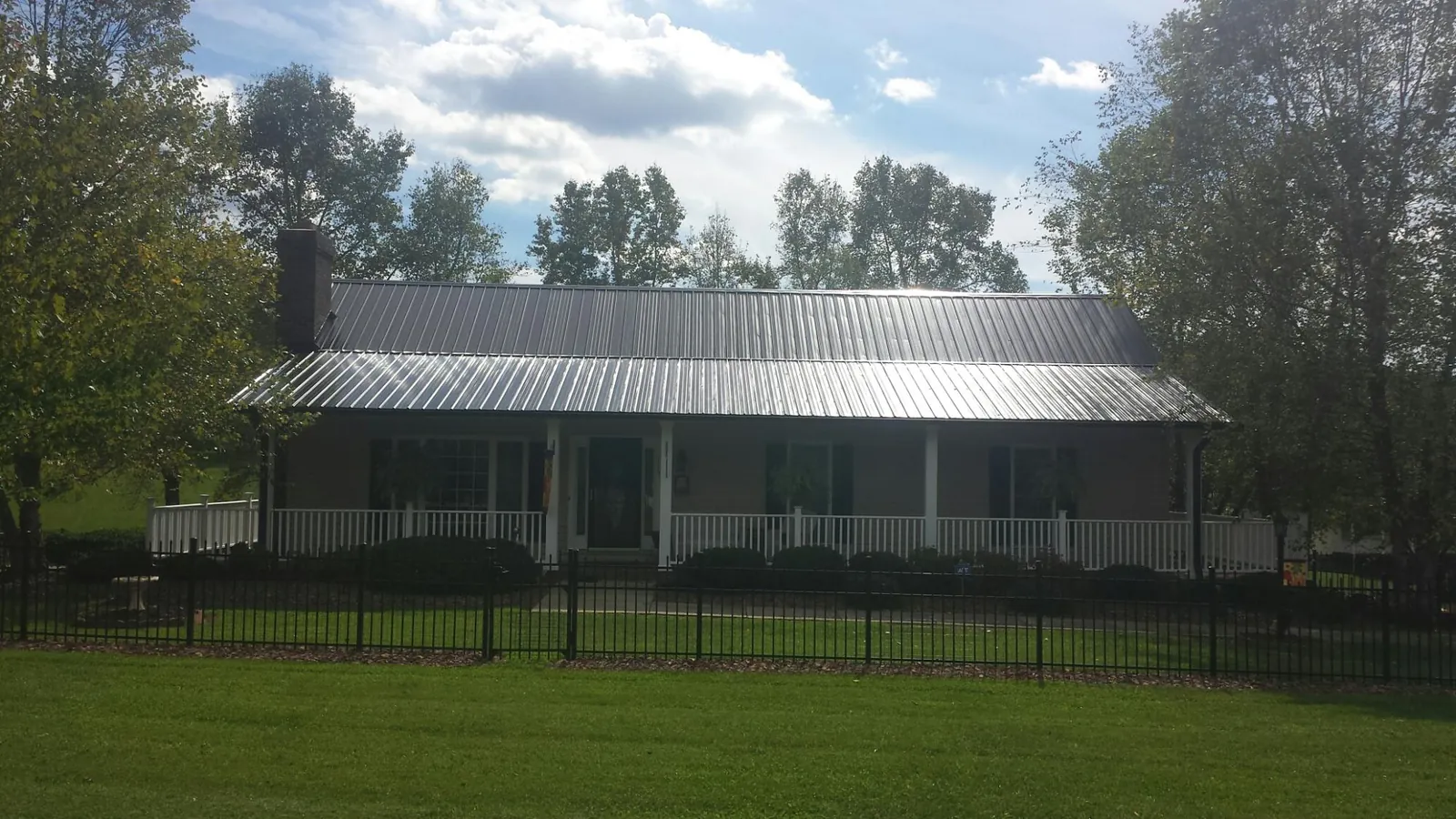 Gray metal roof on a brick ranch with a full width front porch — Gutter Guard Installation work by our crew in Reading
